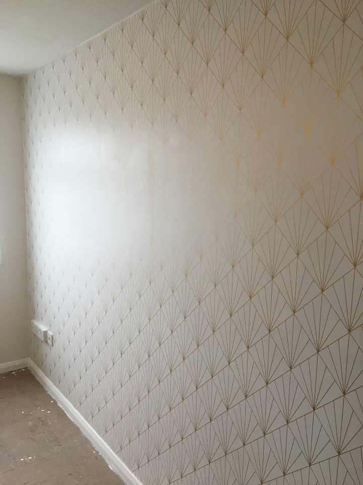 Wall covered in white wallpaper with a gold geometric pattern.