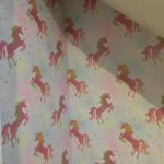 Under stairs wall wallpapered with shiny pink unicorns.