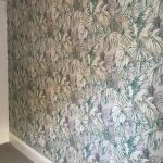 Bedroom wall covered in grey and green jungle wallpaper.