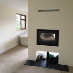Modern solid fuel fireplace separating a dining room and lounge.