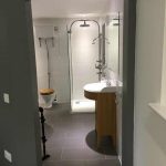 Bathroom with high level cistern toilet, shower cubicle and vanity sink.