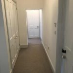 Long hallway with doors off on each side and a door at the end.