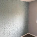 Bedroom with a feature wall in pale grey branch effect wallpaper.