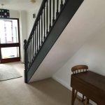 Hallway with grey banisters and white walls.