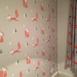Bedroom wall with grey wallpaper with orange foxes and trees.