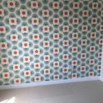 Bedroom wall with Orla Kiely geometric green and orange patterned wallpaper.