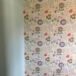 Wallpapered feature wall with flowers and other walls are green.