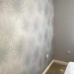 Bedroom wall with starburst grey wallpaper.